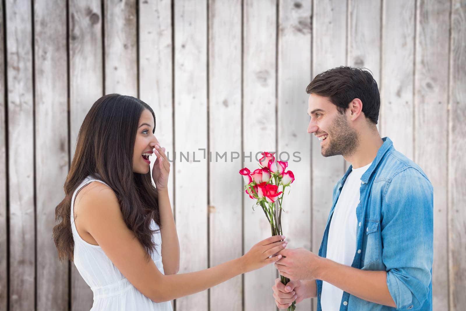 Happy hipster giving his girlfriend roses against wooden planks