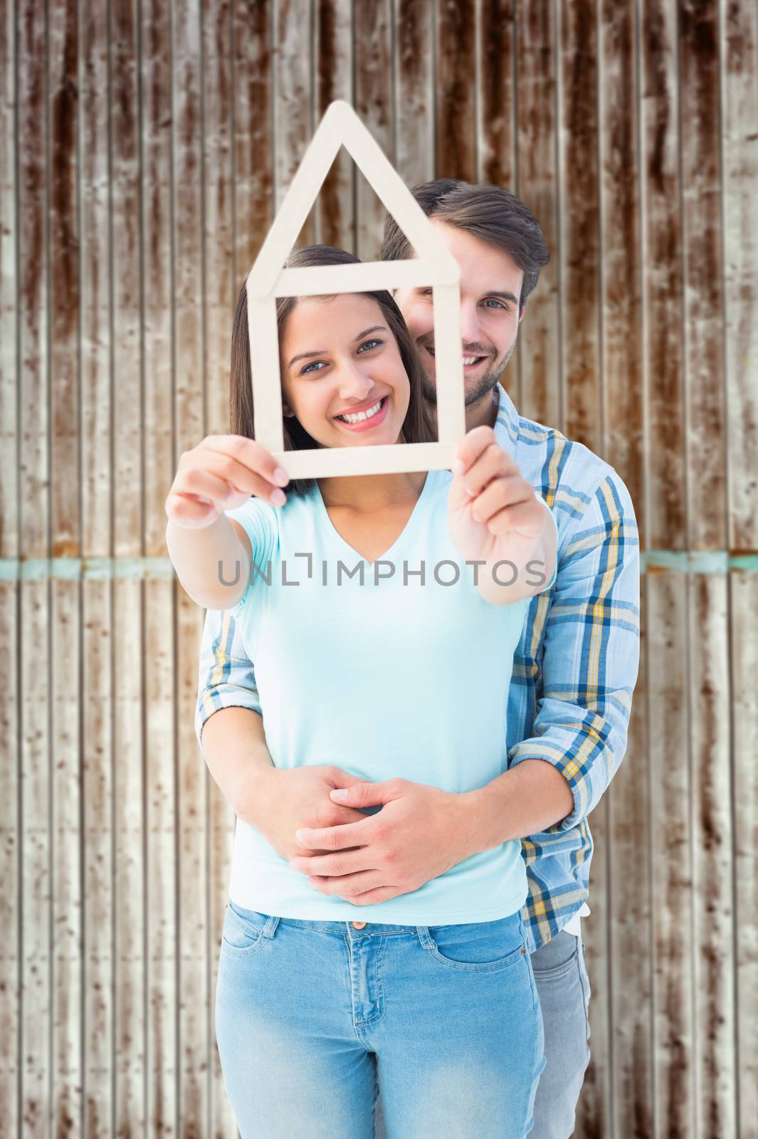 Happy young couple with house shape against wooden planks