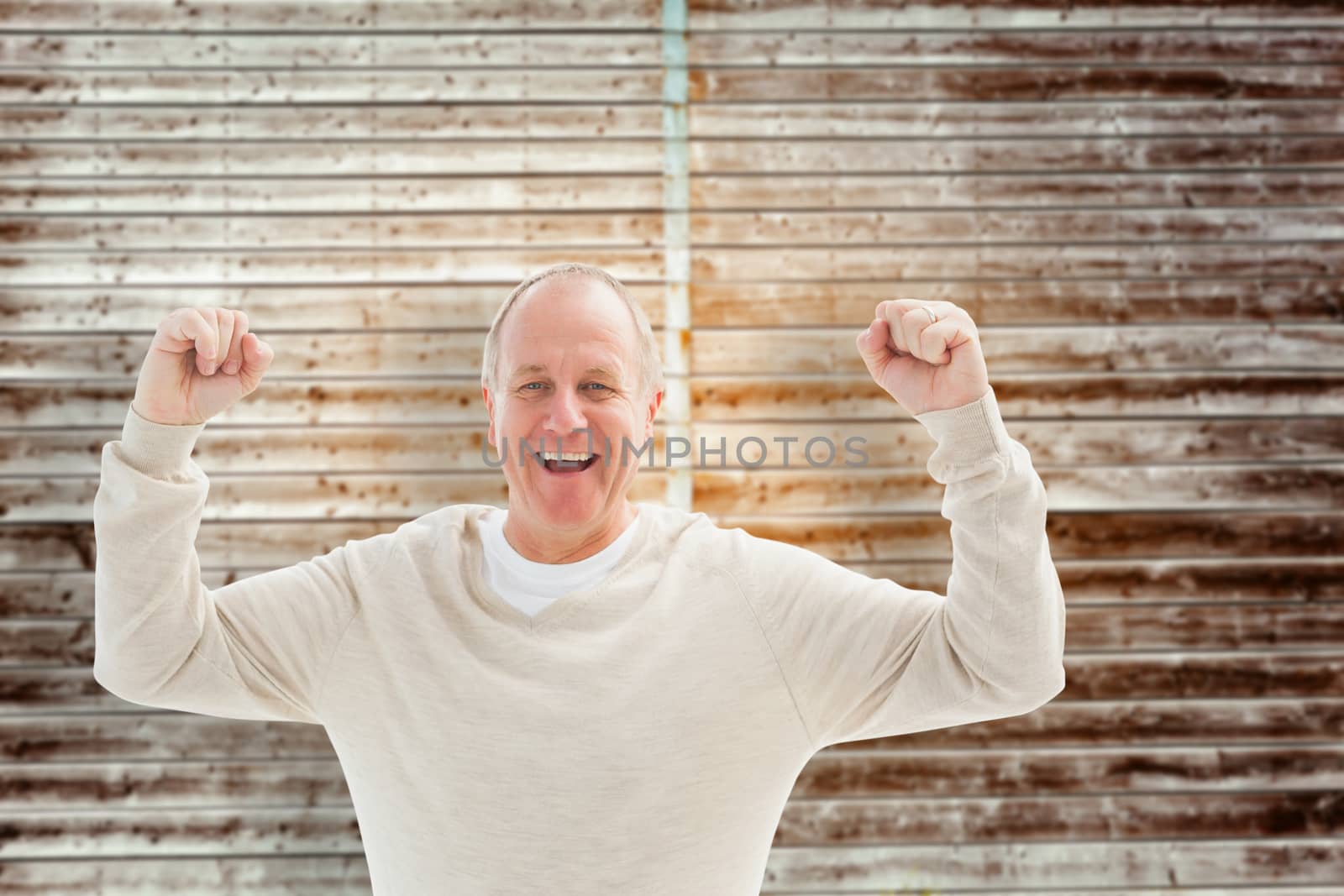 Happy mature man cheering at camera against wooden planks