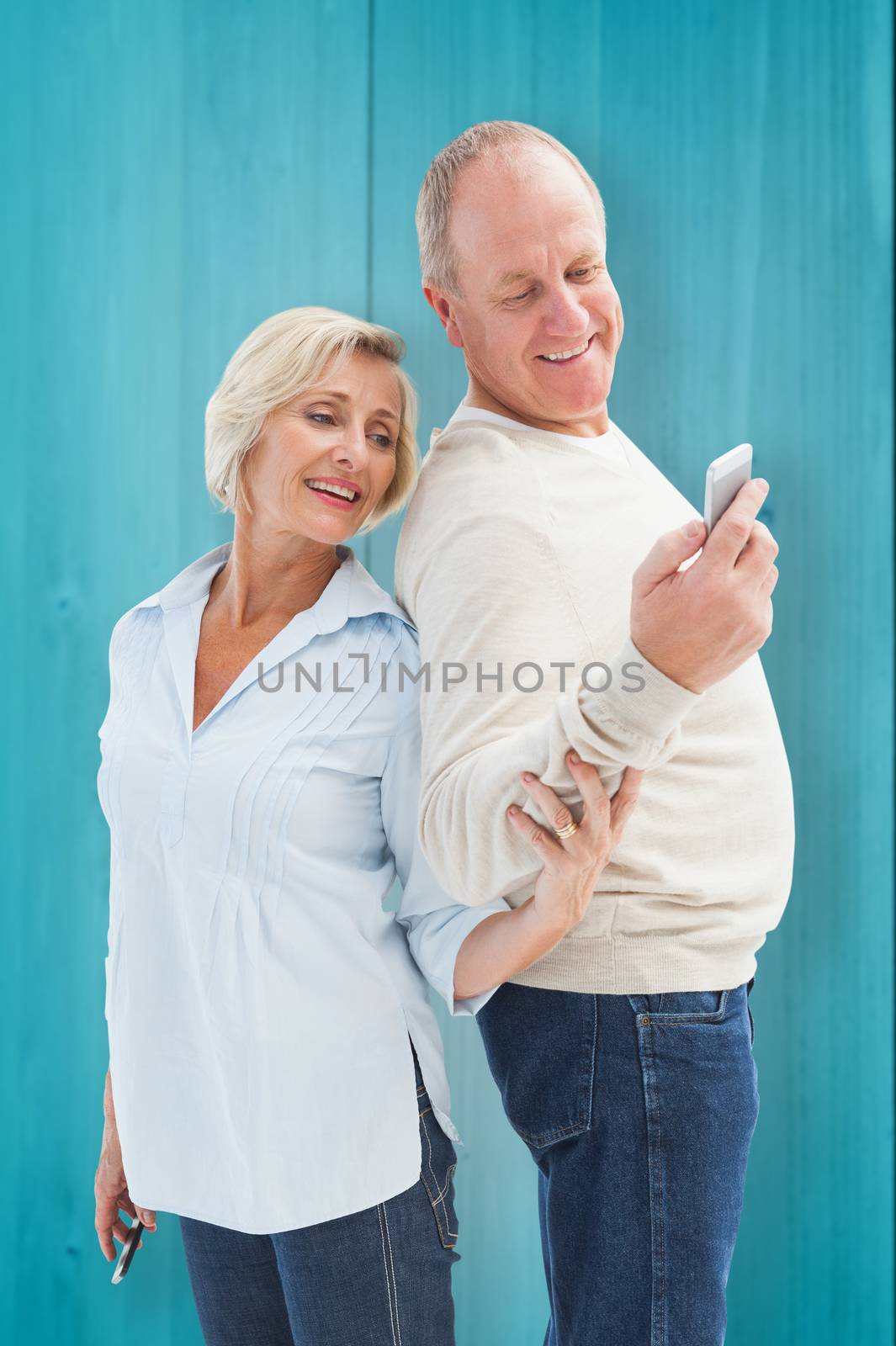 Happy mature couple looking at smartphone together against wooden planks background