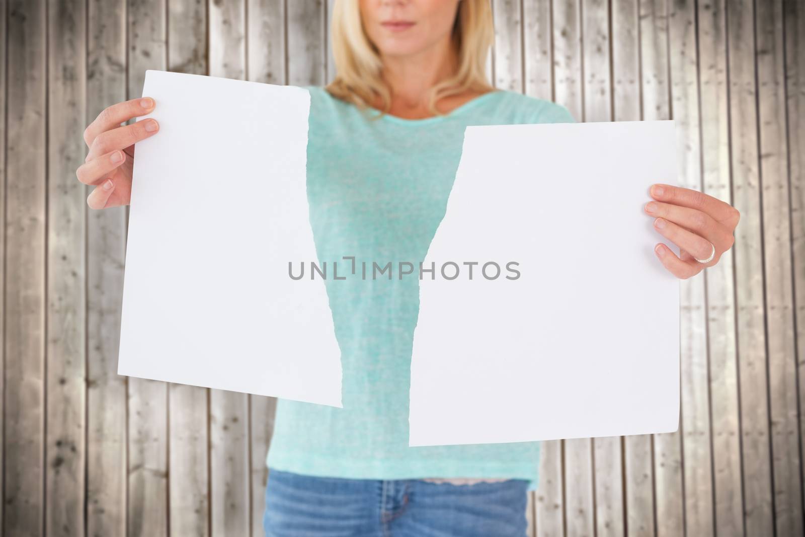 Serious woman holding torn sheet of paper against wooden planks background