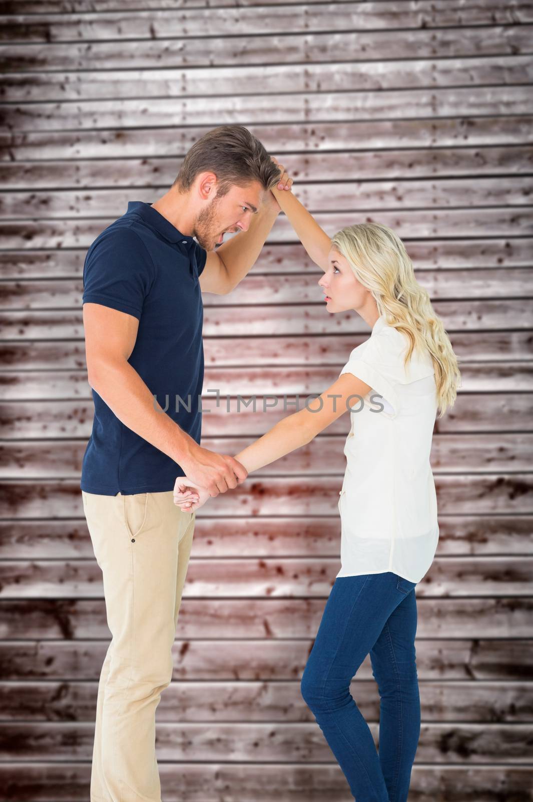 Angry man overpowering his girlfriend against wooden planks