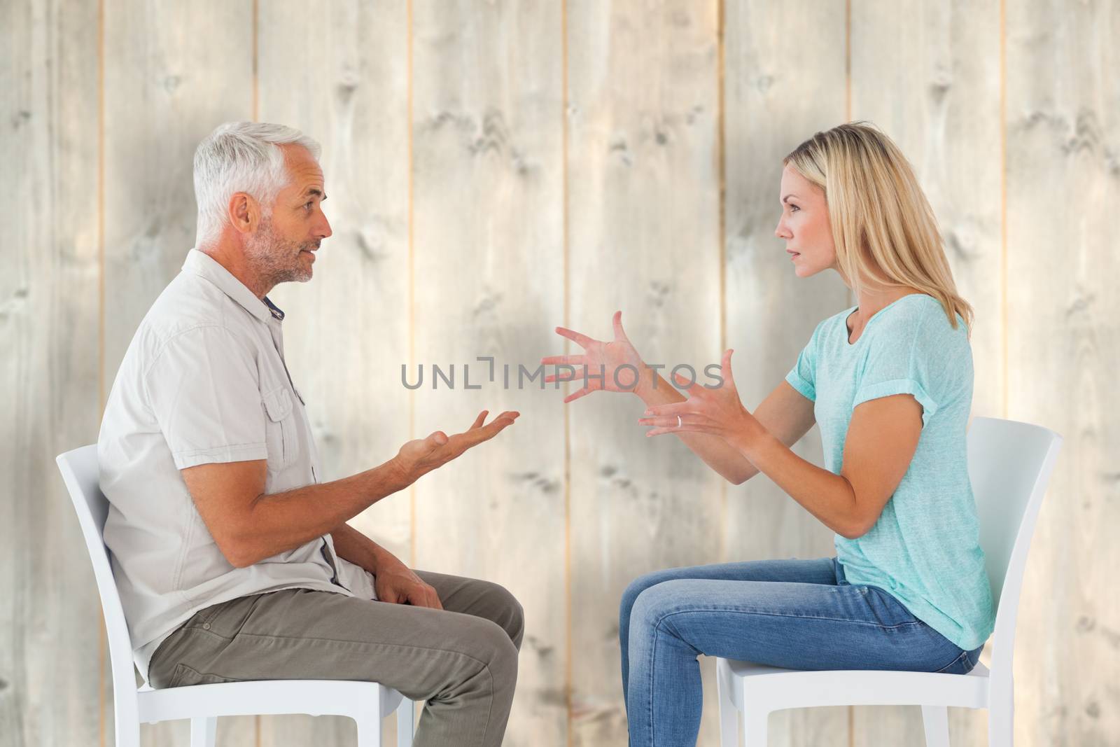 Composite image of unhappy couple sitting on chairs having an argument by Wavebreakmedia