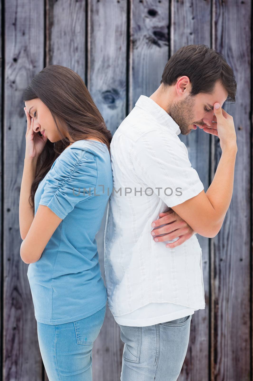 Upset couple not talking to each other after fight against grey wooden planks