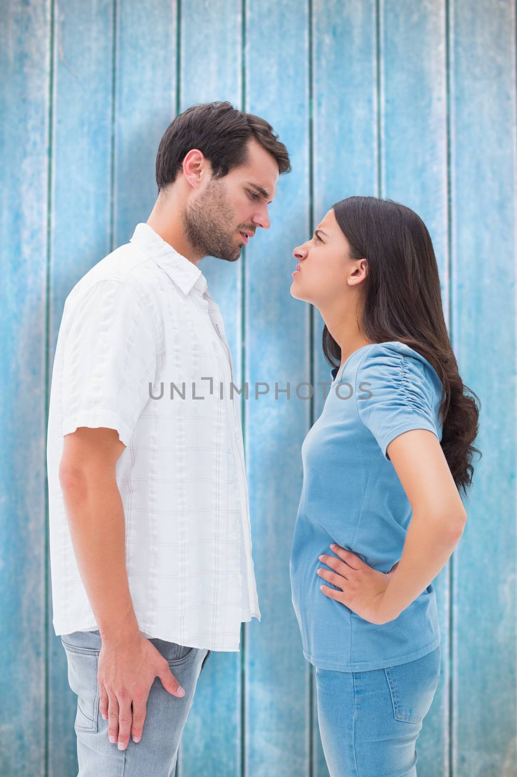 Angry couple staring at each other against wooden planks