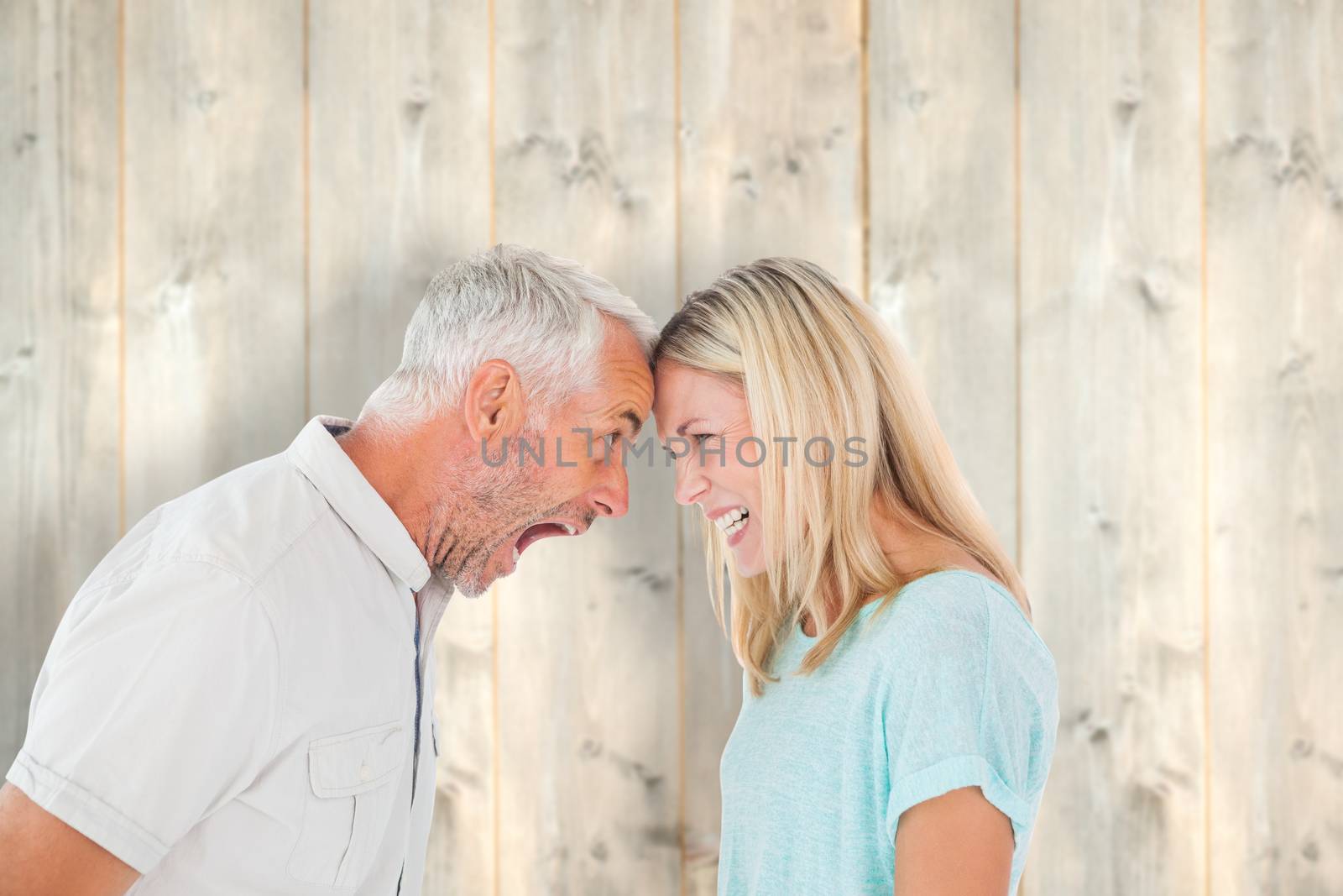 Unhappy couple having an argument  against pale wooden planks