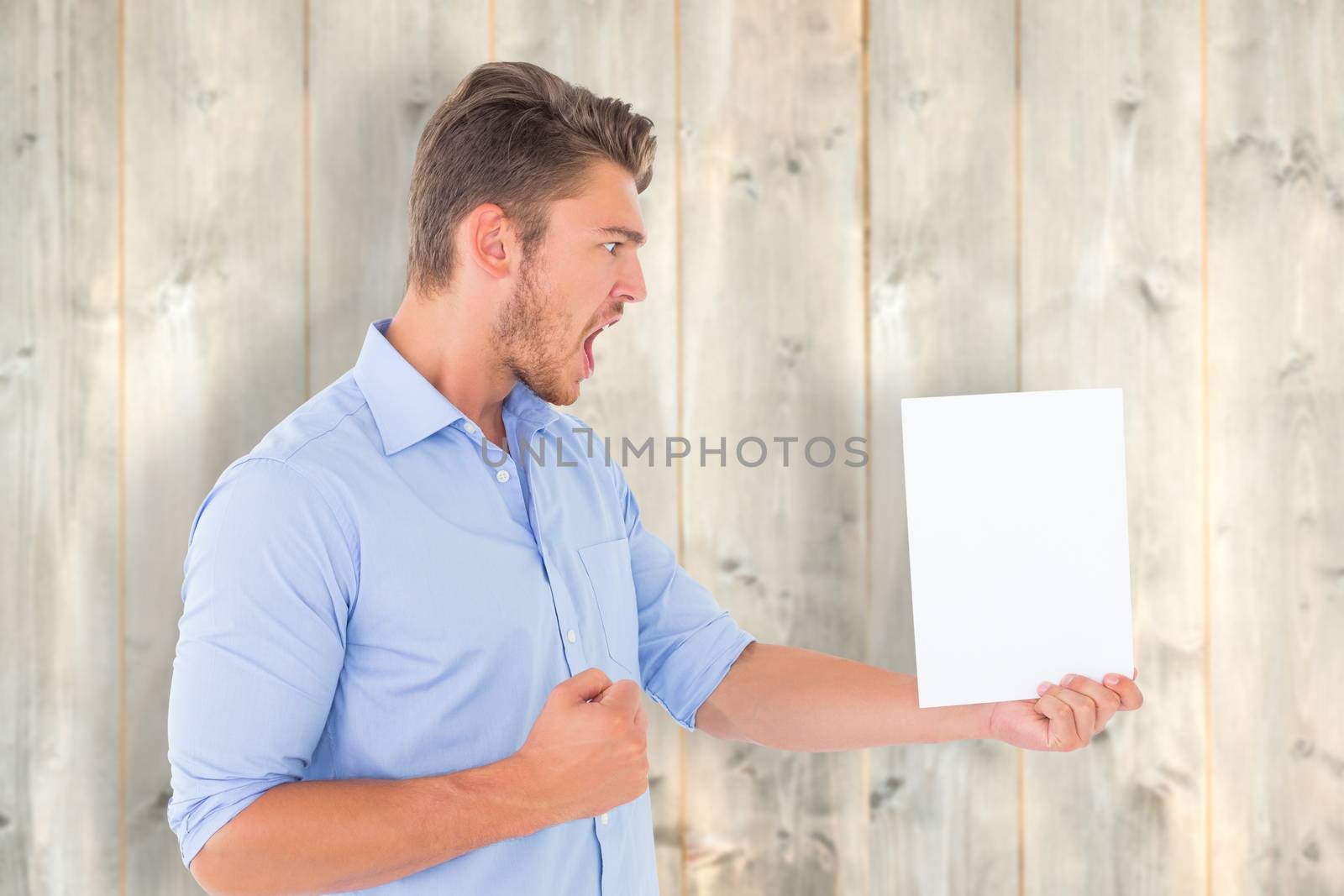 Angry man looking at page against pale wooden planks