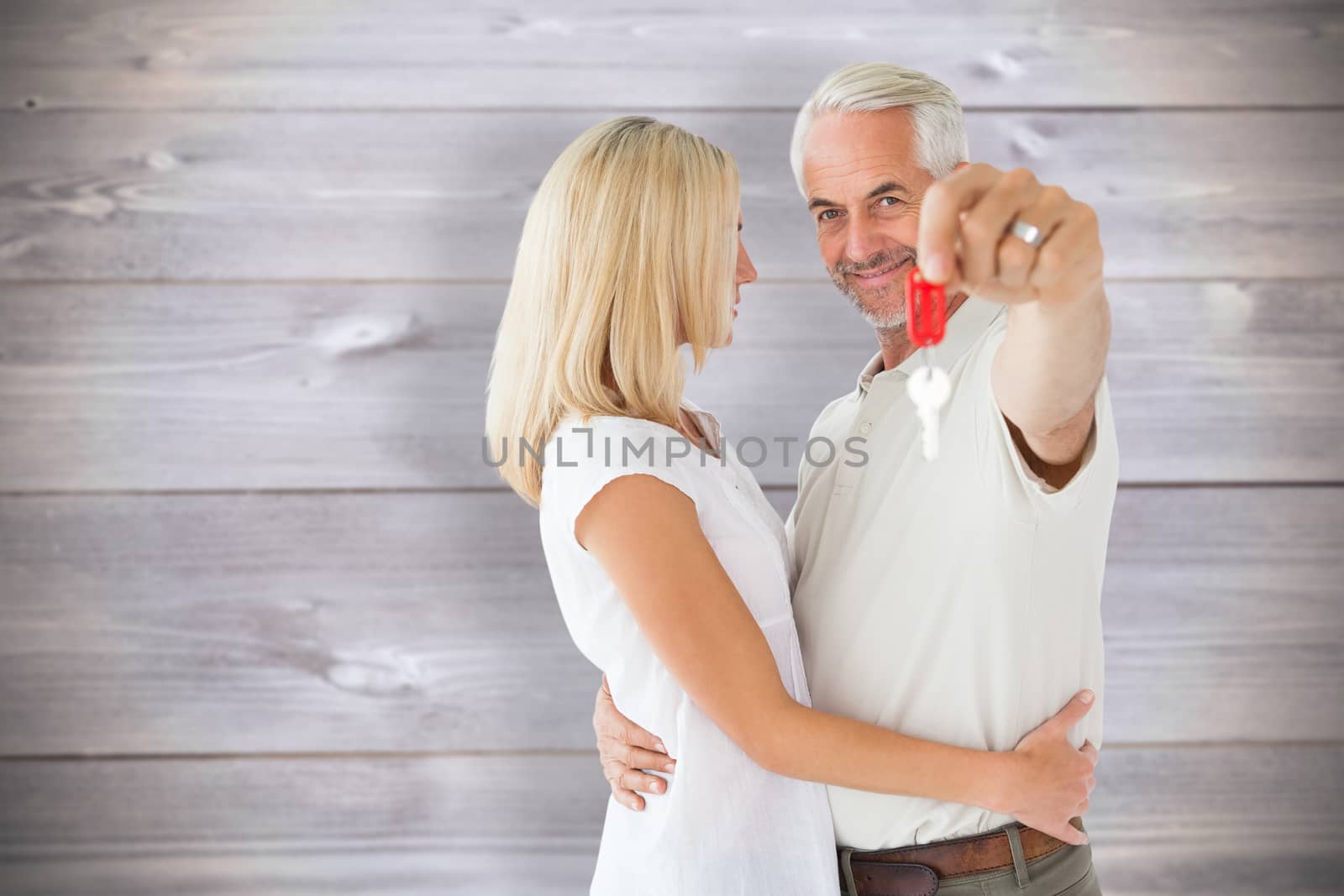 Composite image of happy couple showing their new house key by Wavebreakmedia