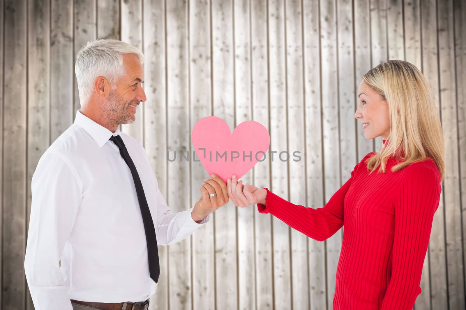 Handsome man getting a heart card form wife against wooden planks background