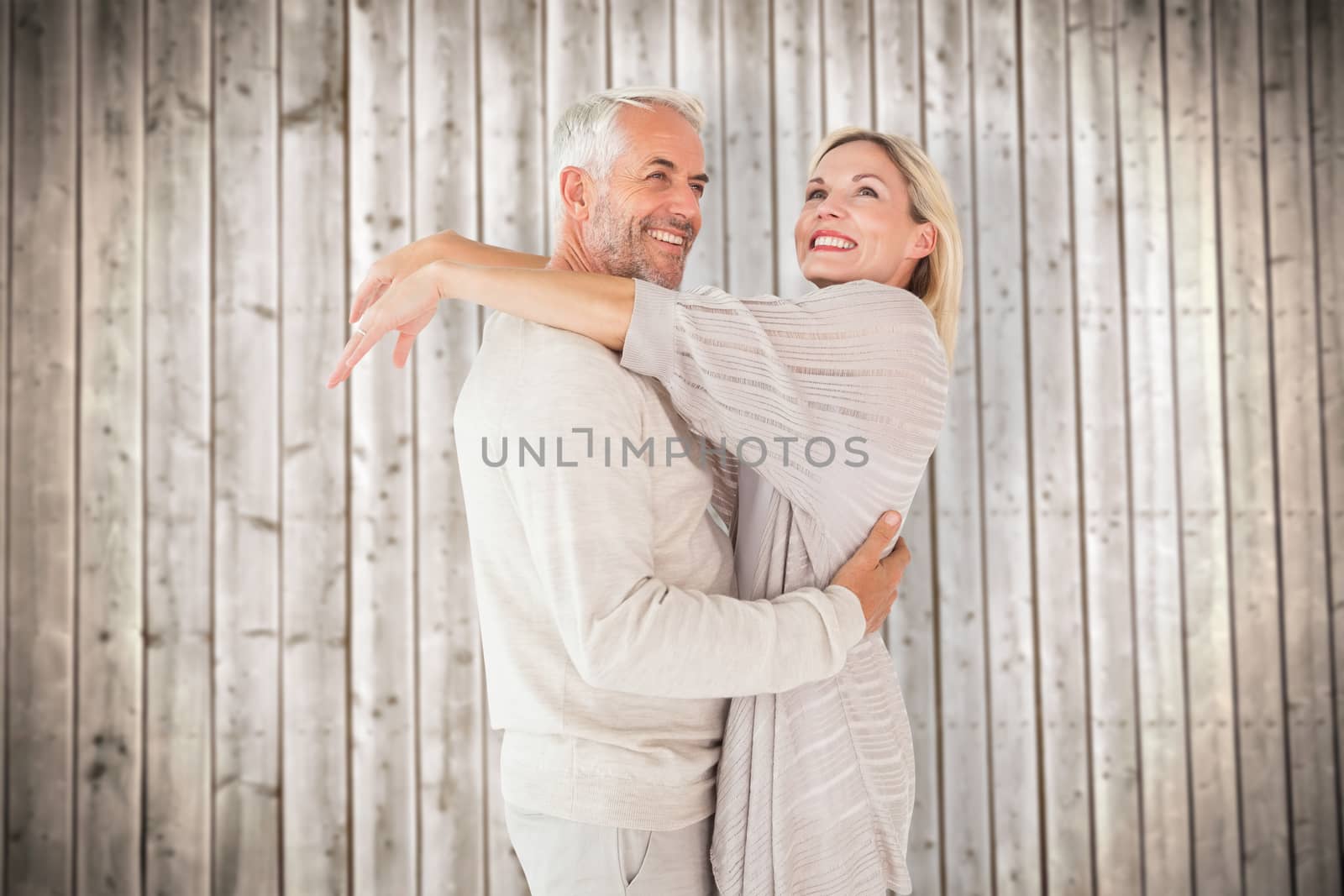 Happy couple standing and hugging against wooden planks background