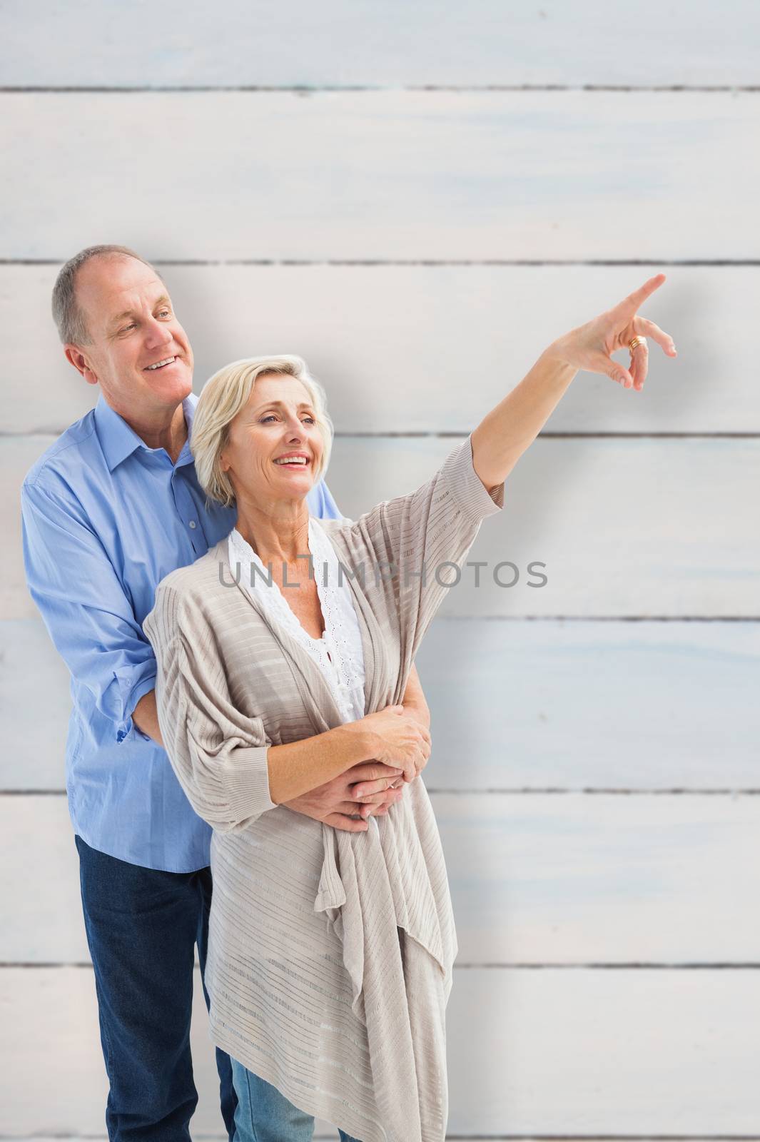 Happy mature couple embracing and looking against wooden planks