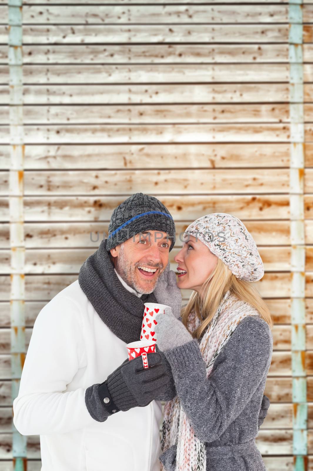 Composite image of happy couple in winter fashion holding mugs by Wavebreakmedia
