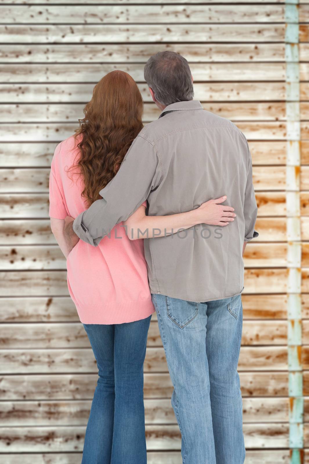 Composite image of casual couple standing arms around by Wavebreakmedia