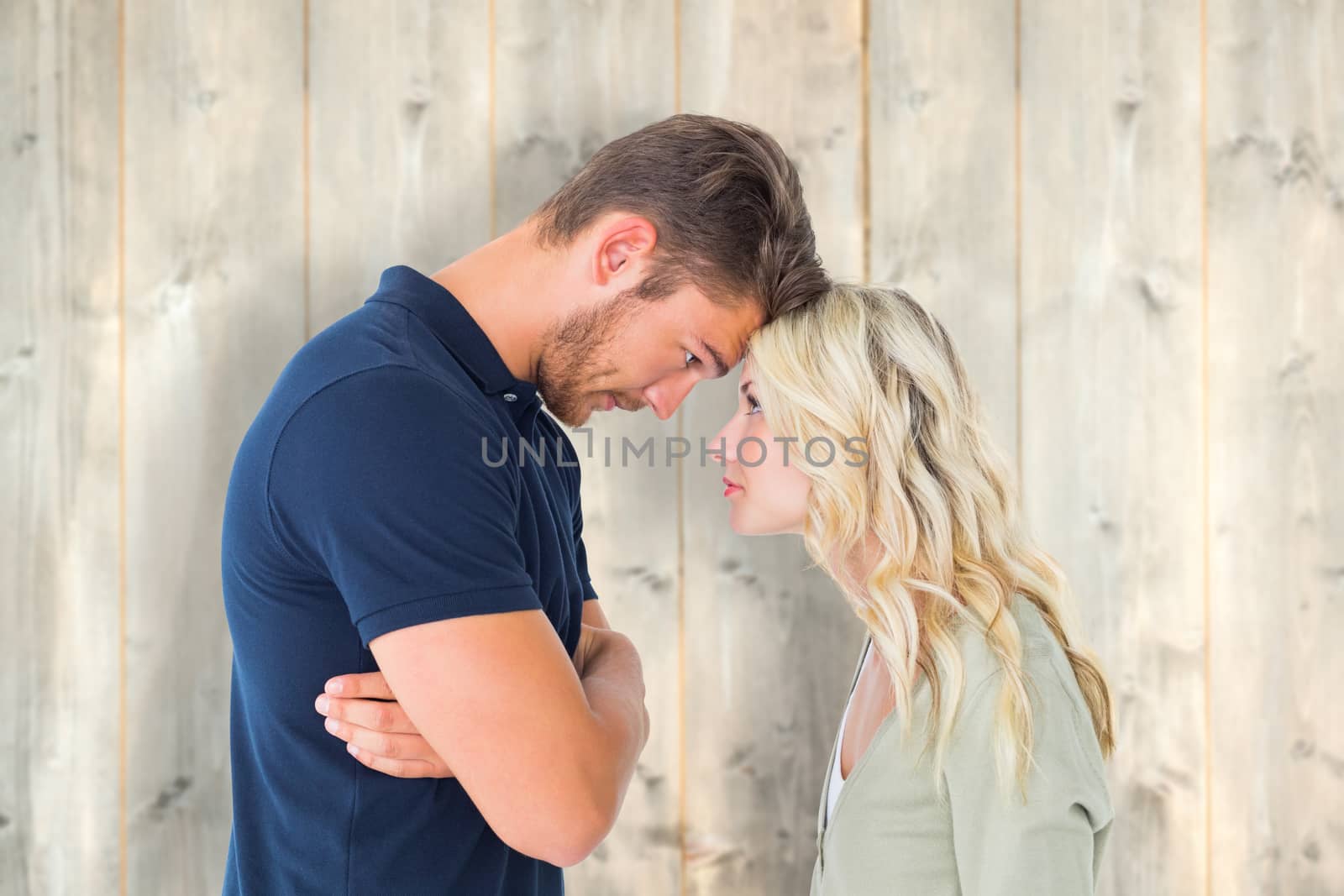 Young couple standing head to head against pale wooden planks