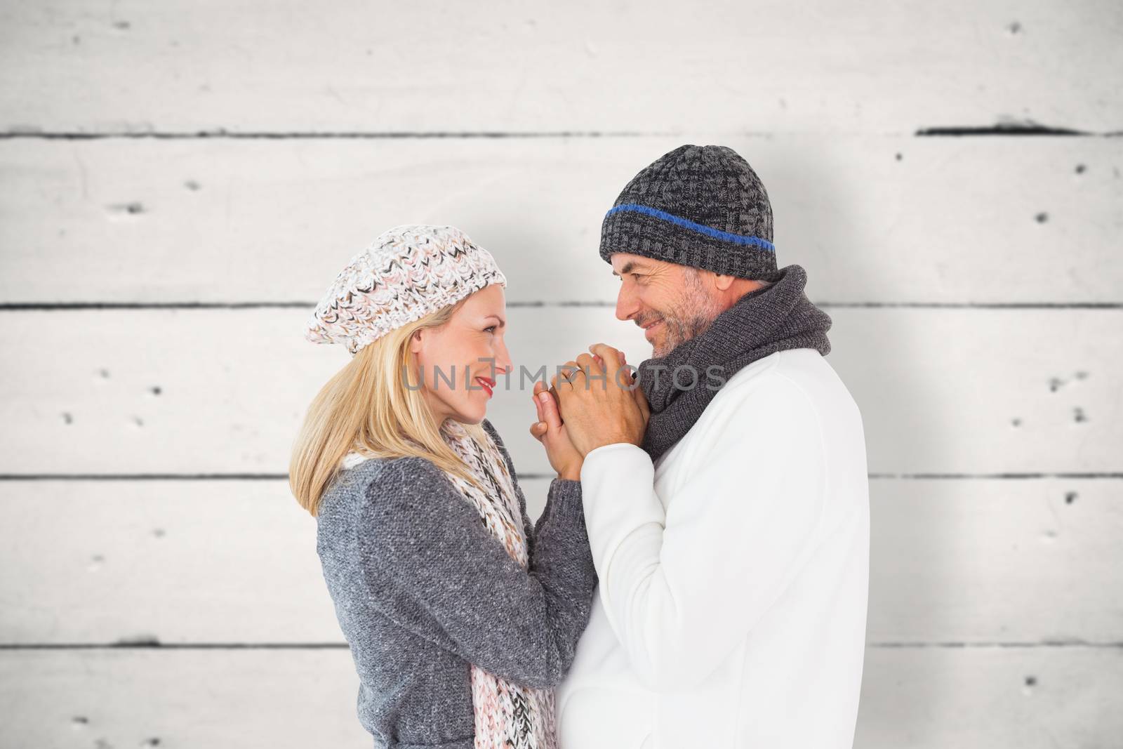 Couple in winter fashion embracing against white wood