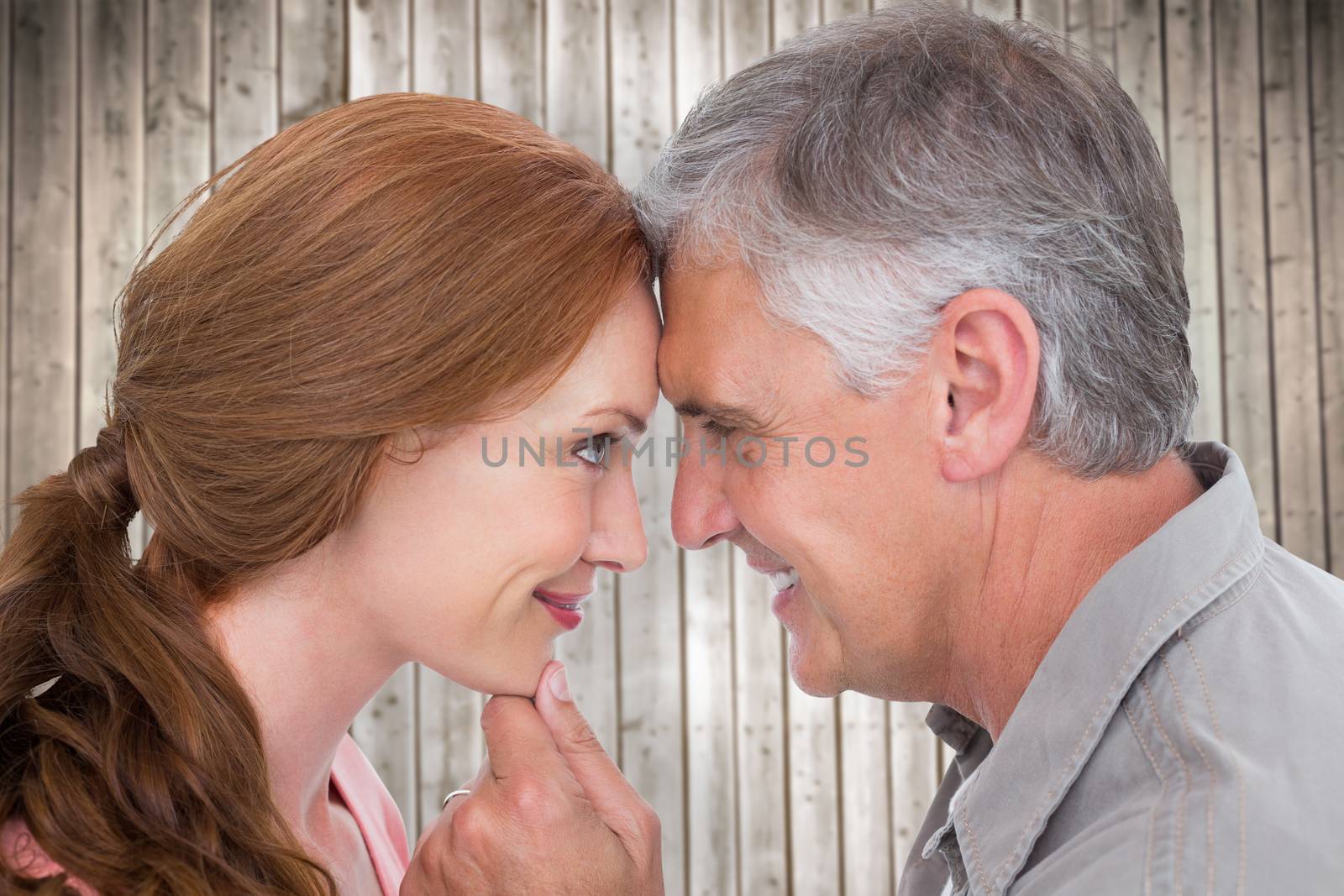 Casual couple smiling at each other against wooden planks background