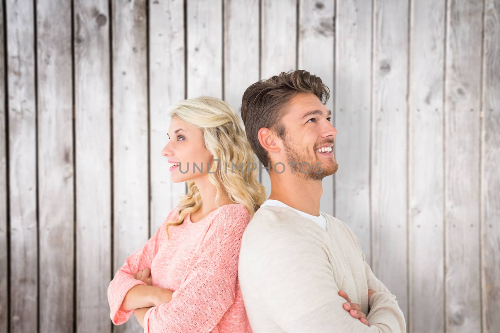 Attractive couple smiling with arms crossed against wooden planks