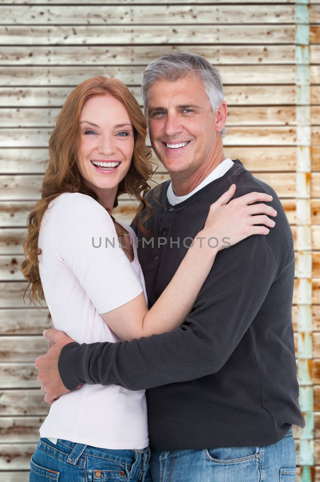 Casual couple smiling at camera against faded pine wooden planks