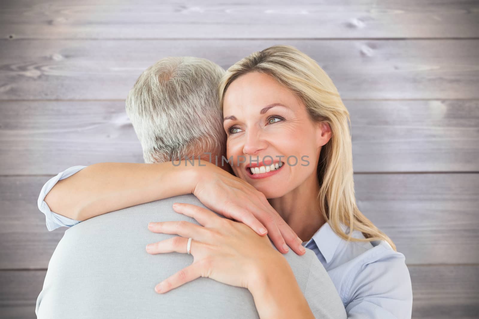 Happy couple standing and hugging against wooden planks background