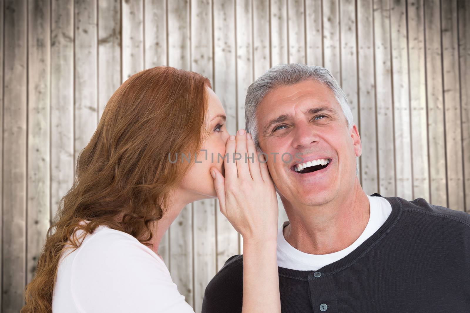 Woman telling secret to her partner against wooden planks background