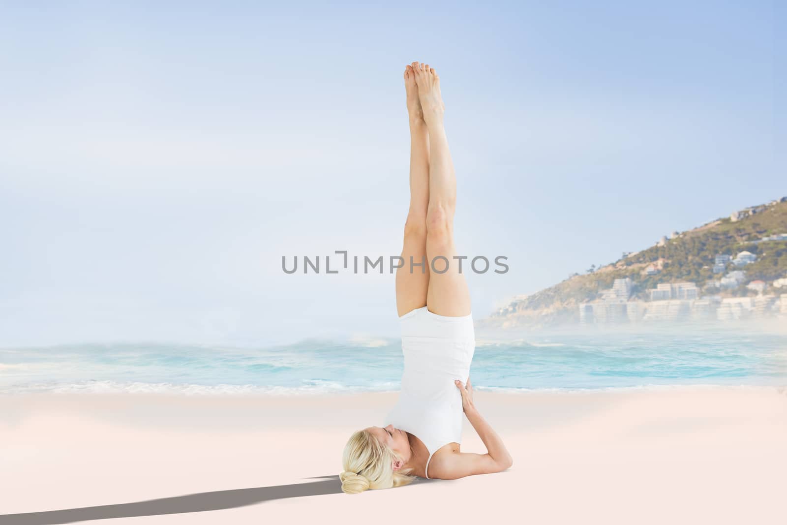 Fit young woman doing the shoulder stand pose against beautiful beach and blue sky