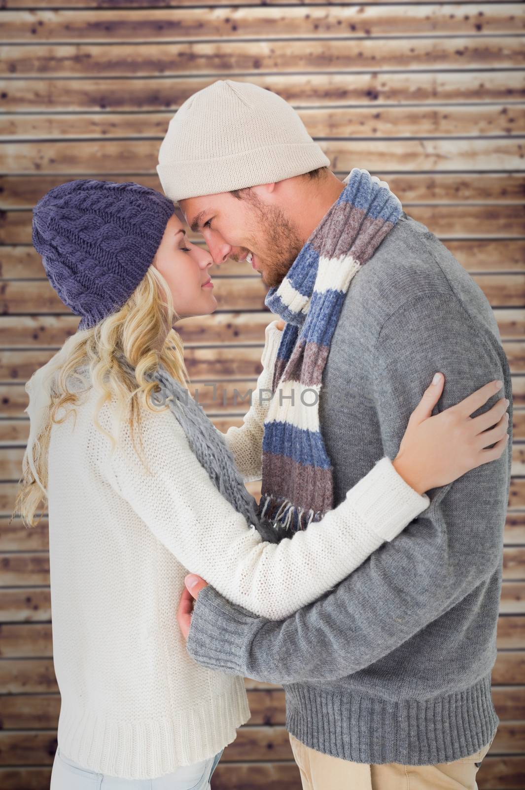 Composite image of attractive couple in winter fashion hugging by Wavebreakmedia