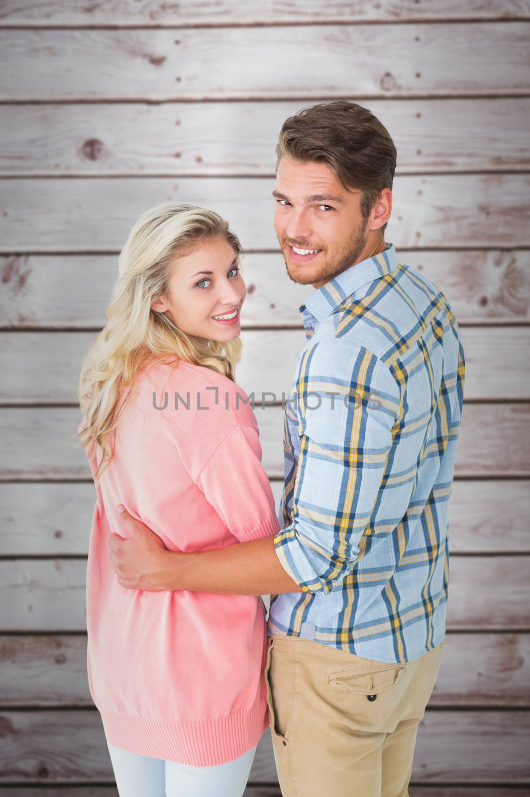 Attractive couple turning and smiling at camera against wooden planks