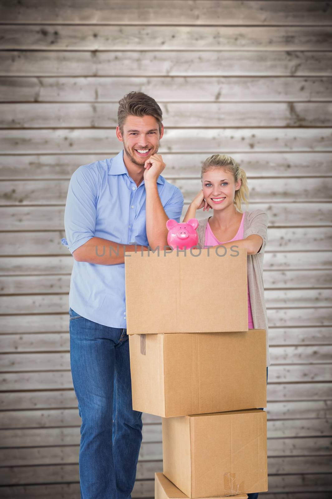 Attractive young couple leaning on boxes with piggy bank against wooden planks background