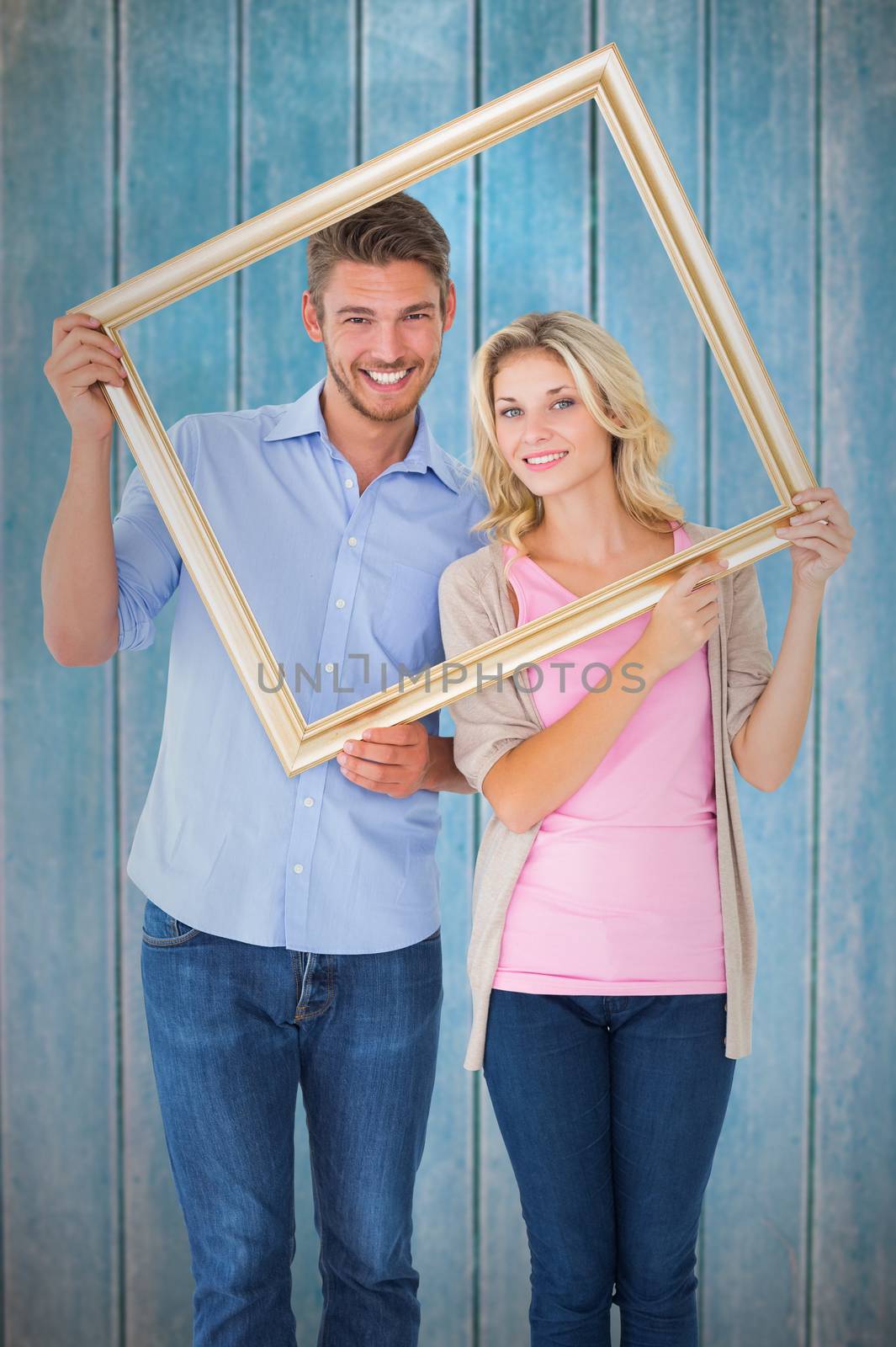 Composite image of attractive young couple holding picture frame by Wavebreakmedia