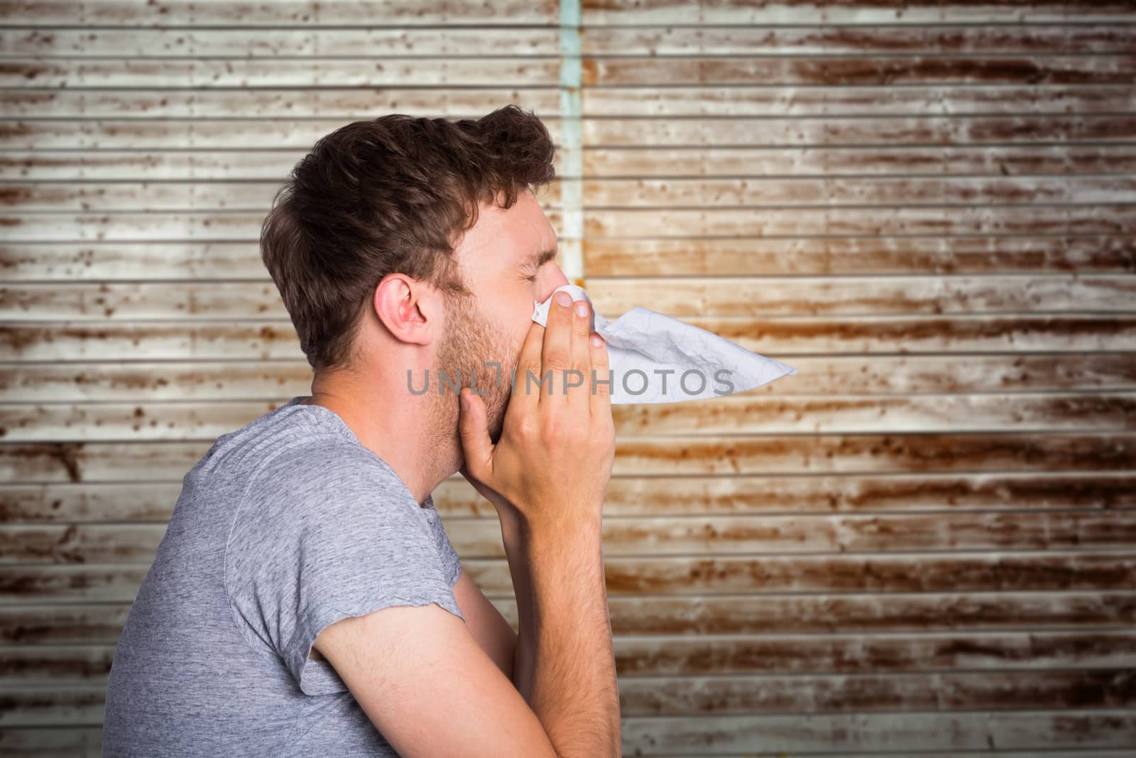 Close up side view of man blowing nose against wooden planks