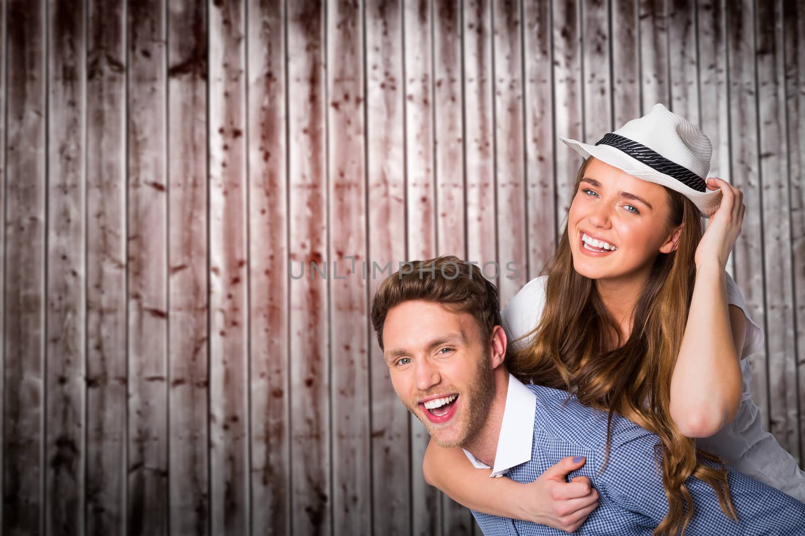 Smiling young man carrying woman against wooden planks