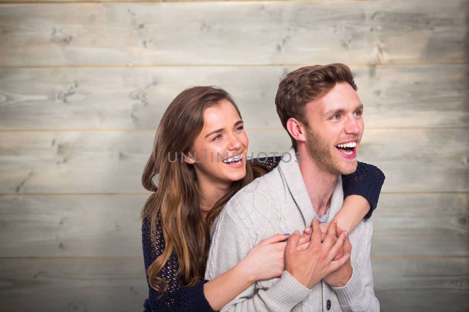 Cheerful young couple embracing against bleached wooden planks background