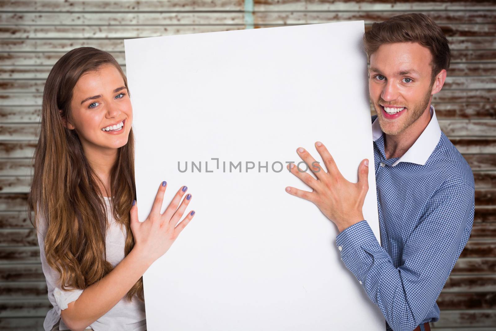 Happy young couple with blank board against wooden planks