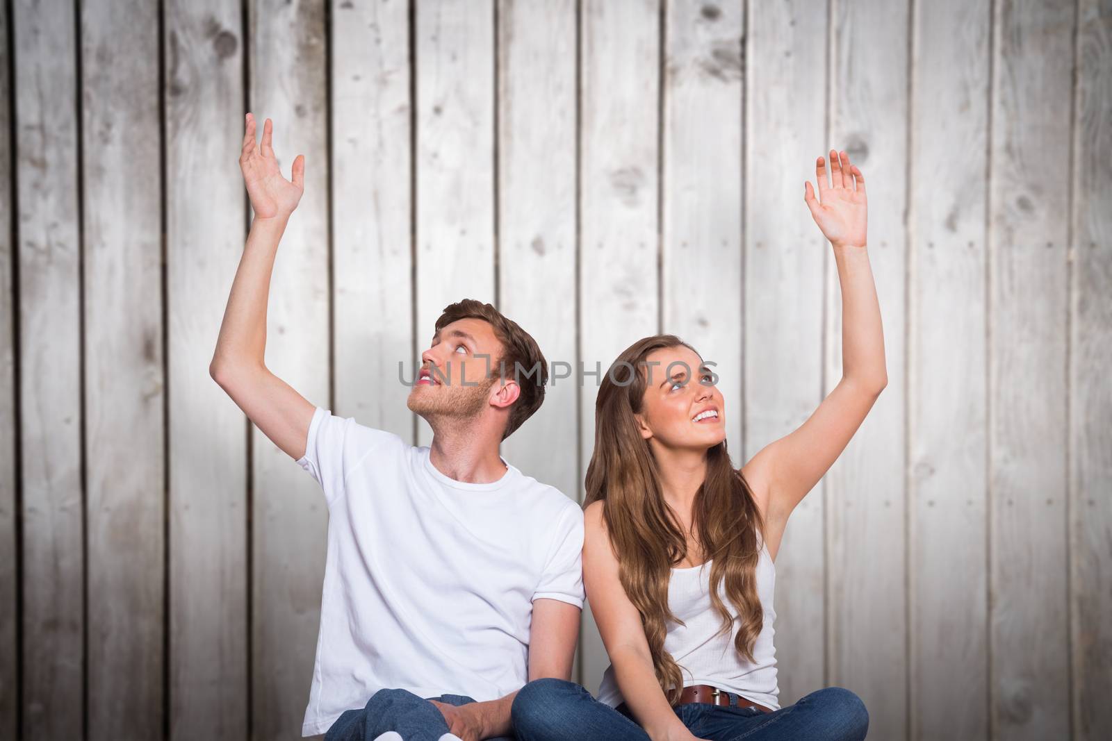 Happy young couple with hands raised against wooden planks