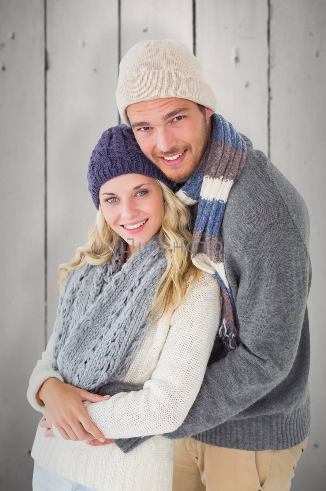 Attractive couple in winter fashion hugging against white wood