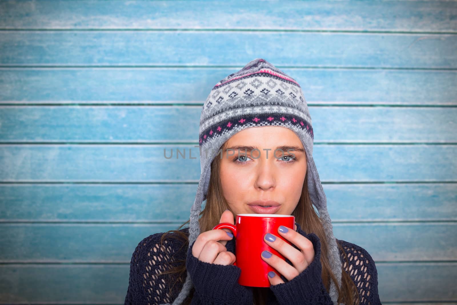 Composite image of beautiful woman in warm clothing drinking coffee by Wavebreakmedia