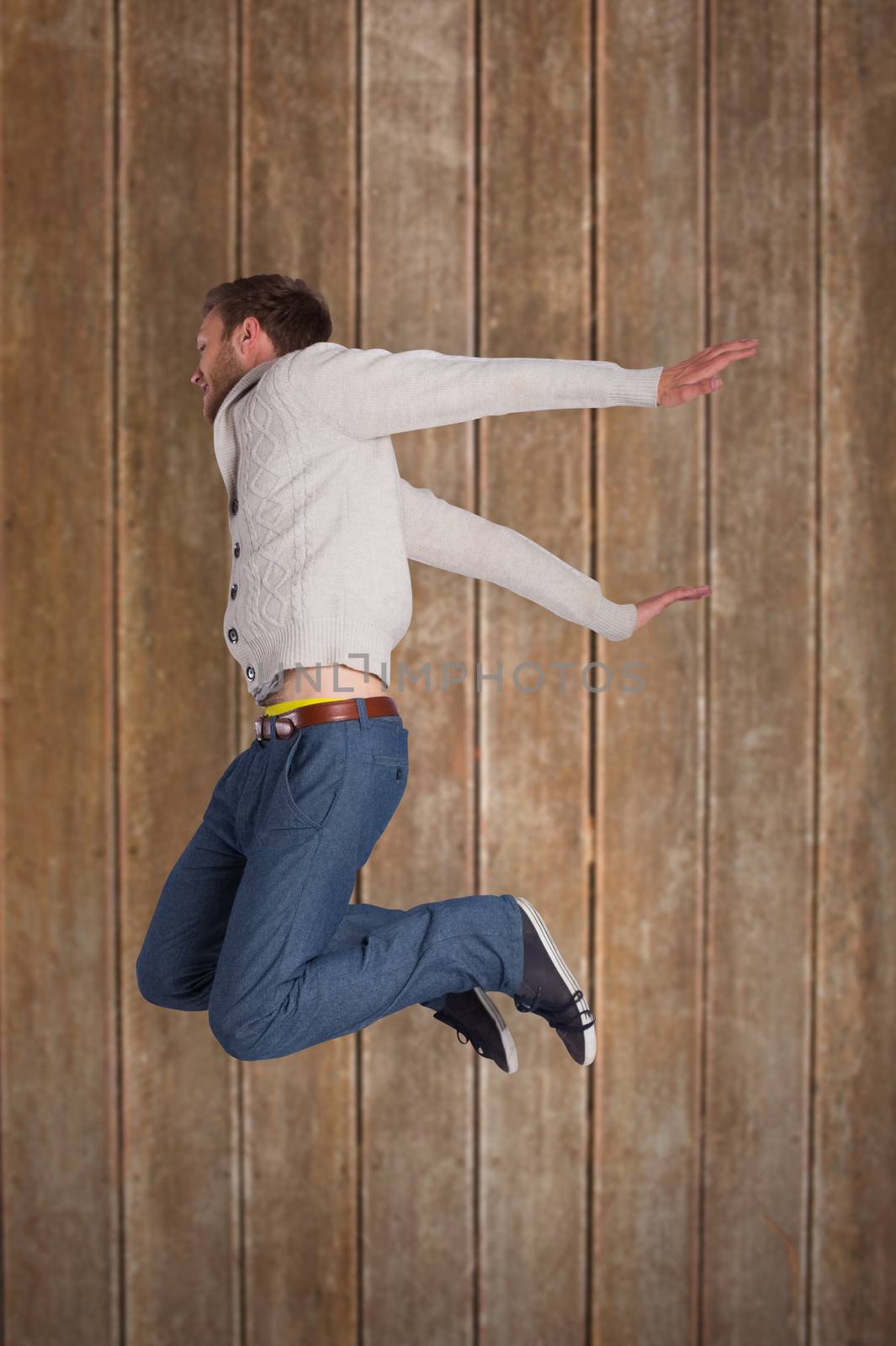 Composite image of full length of cheerful young man jumping by Wavebreakmedia