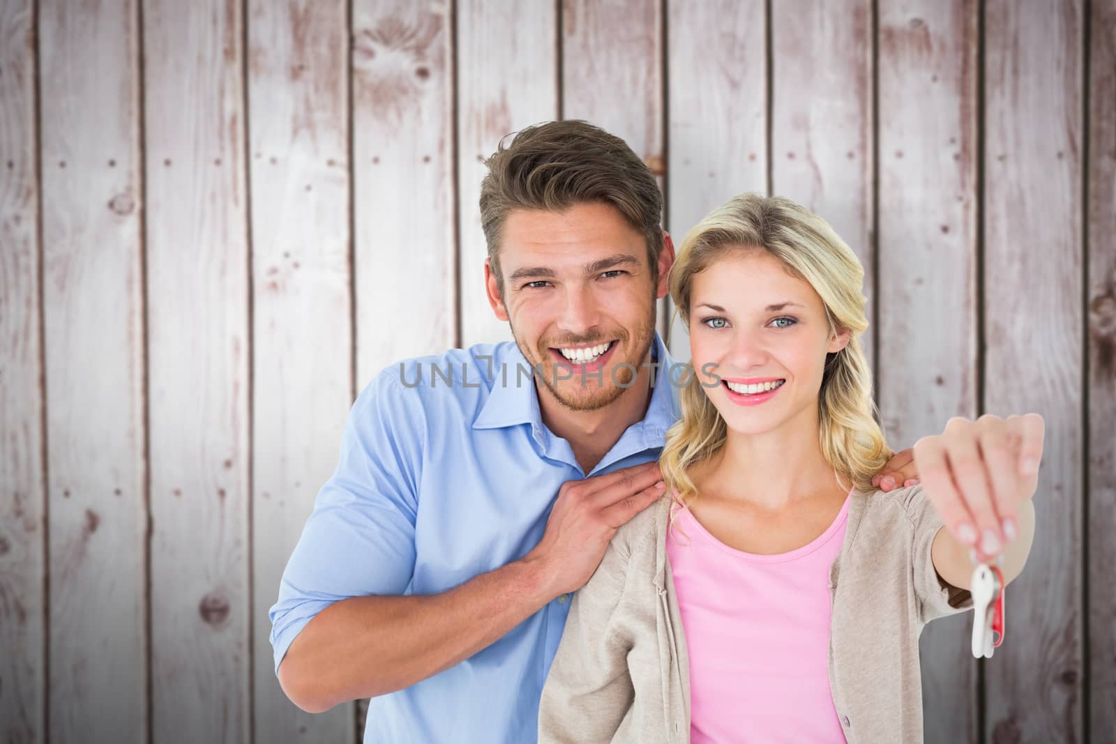 Composite image of attractive young couple showing new house key by Wavebreakmedia