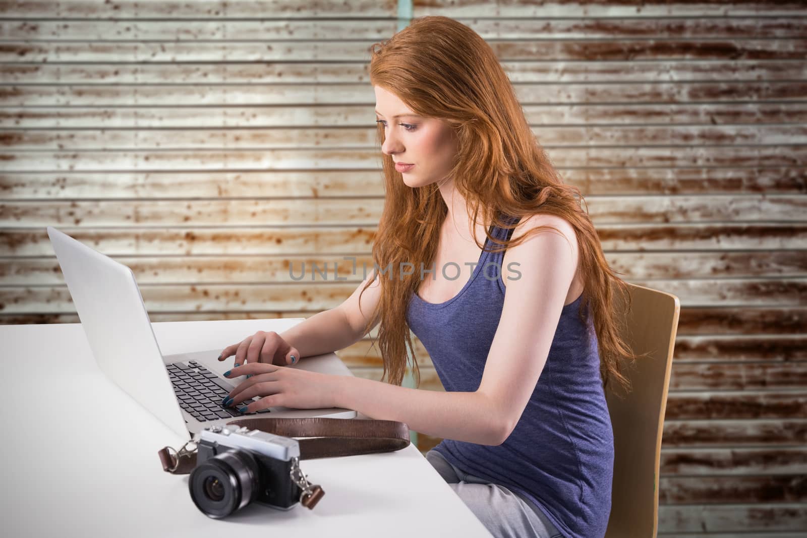 Pretty redhead working on laptop against wooden planks