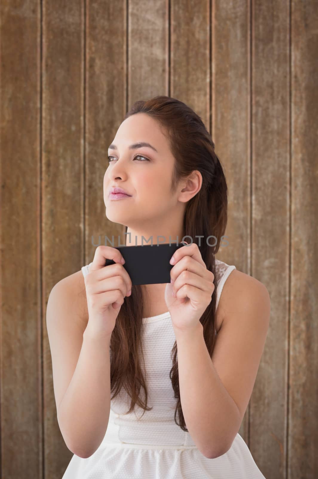 Composite image of thoughtful brunette holding her phone  by Wavebreakmedia