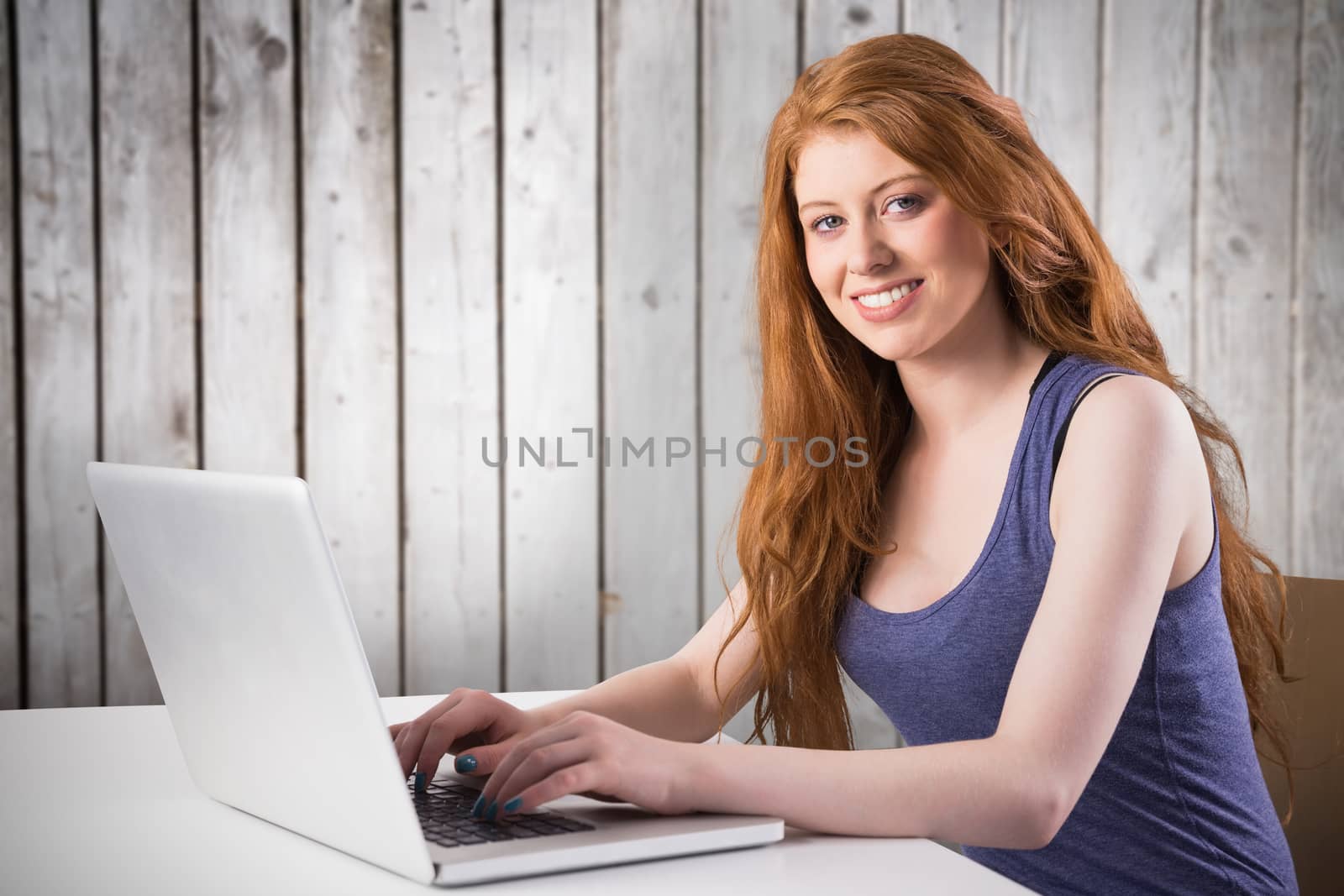 Composite image of pretty redhead working on laptop by Wavebreakmedia