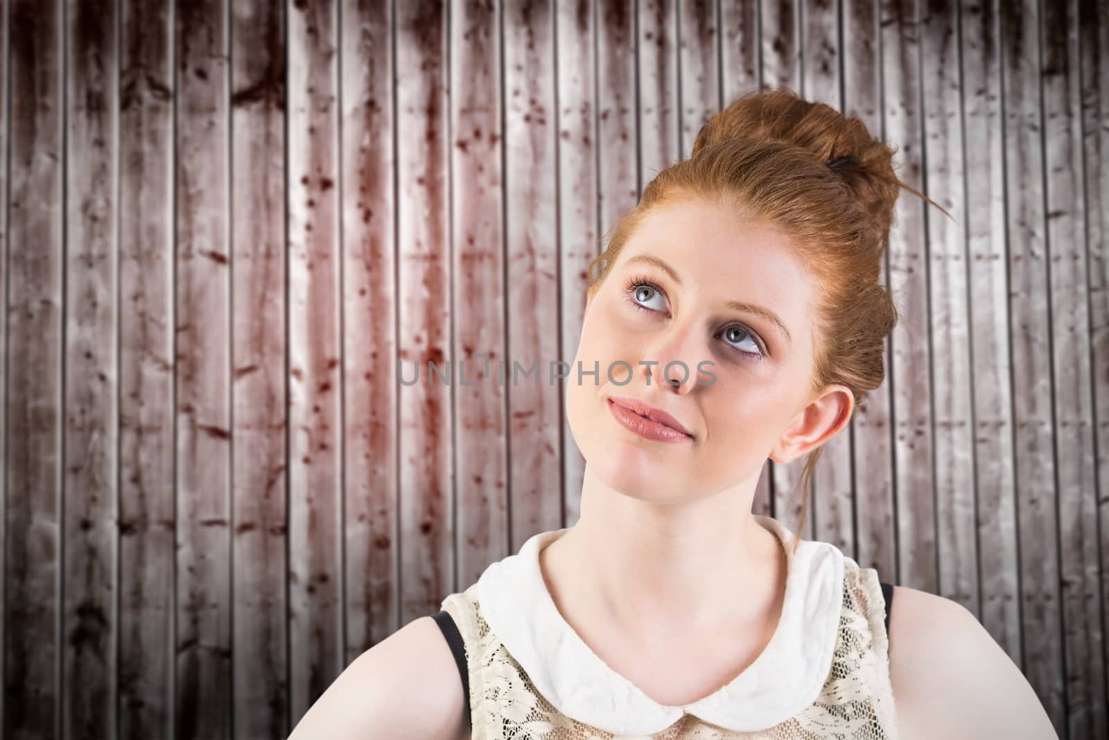 Hipster redhead looking up thinking against wooden planks