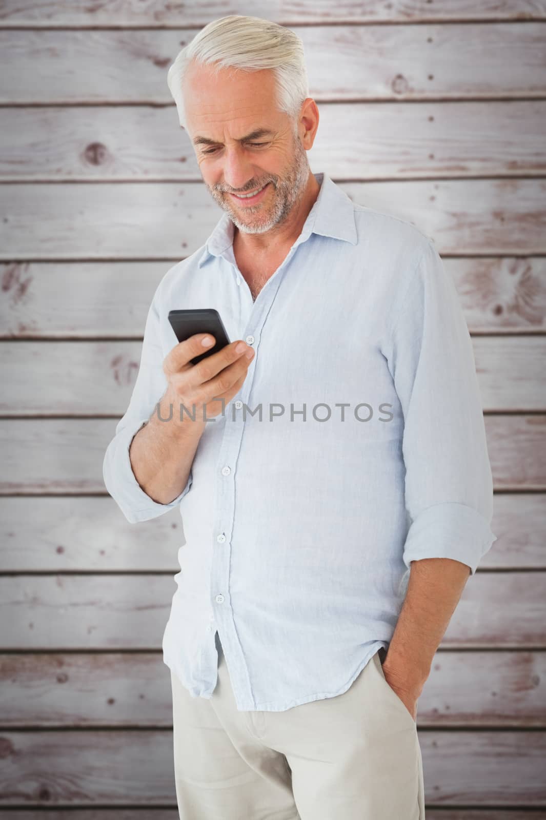 Smiling man sending a text message against wooden planks