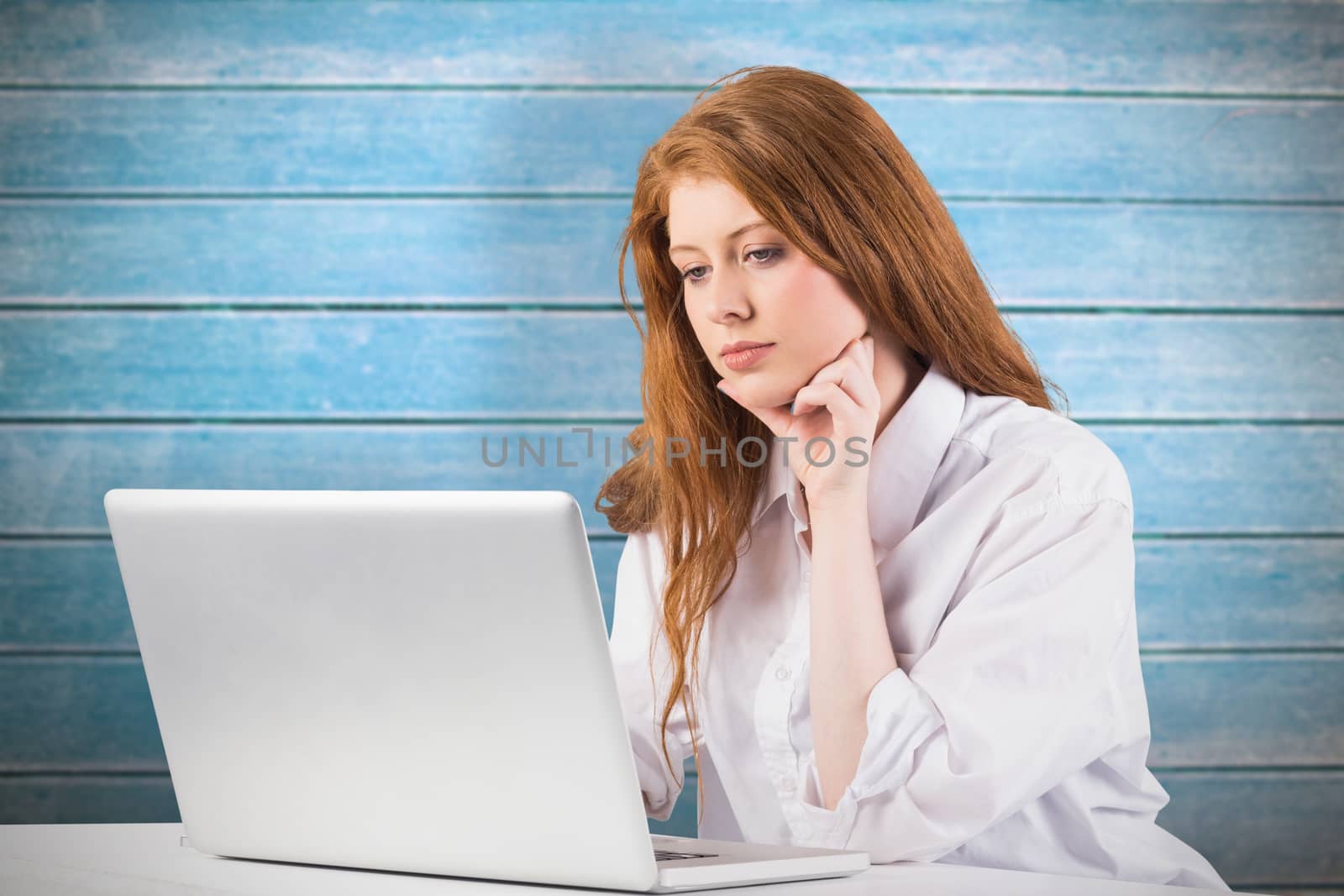 Pretty redhead working on laptop against wooden planks