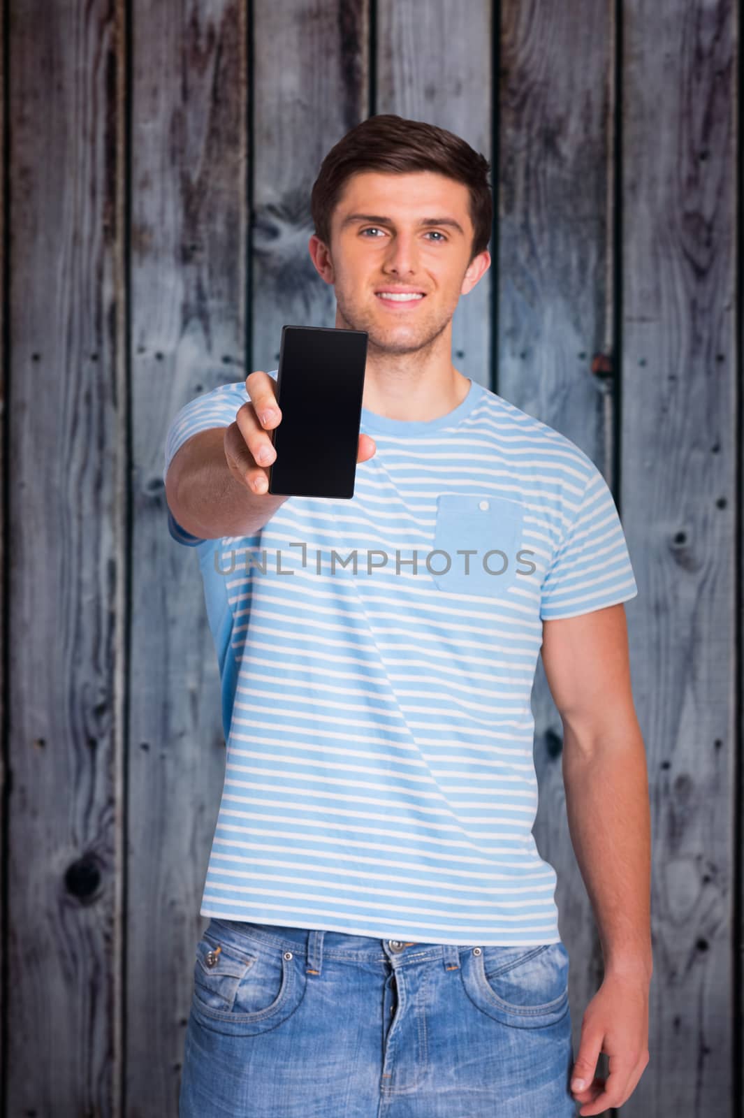 Young man showing phone to camera against grey wooden planks