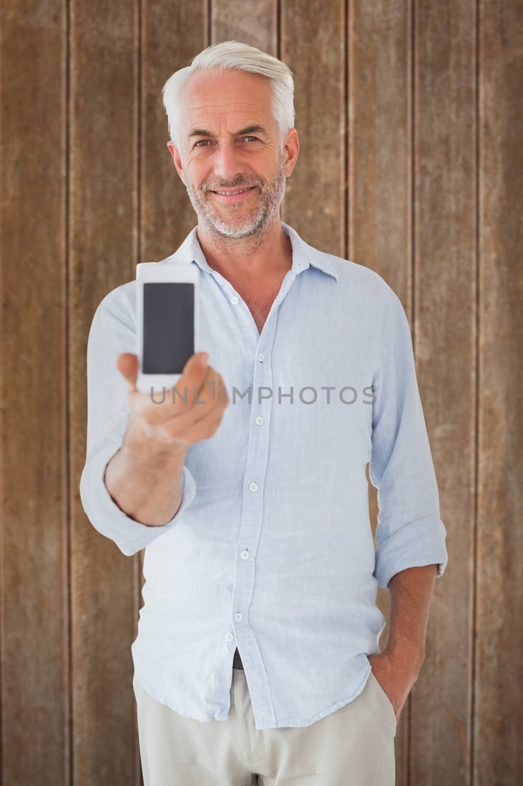 Smiling man showing smartphone to camera against wooden planks background