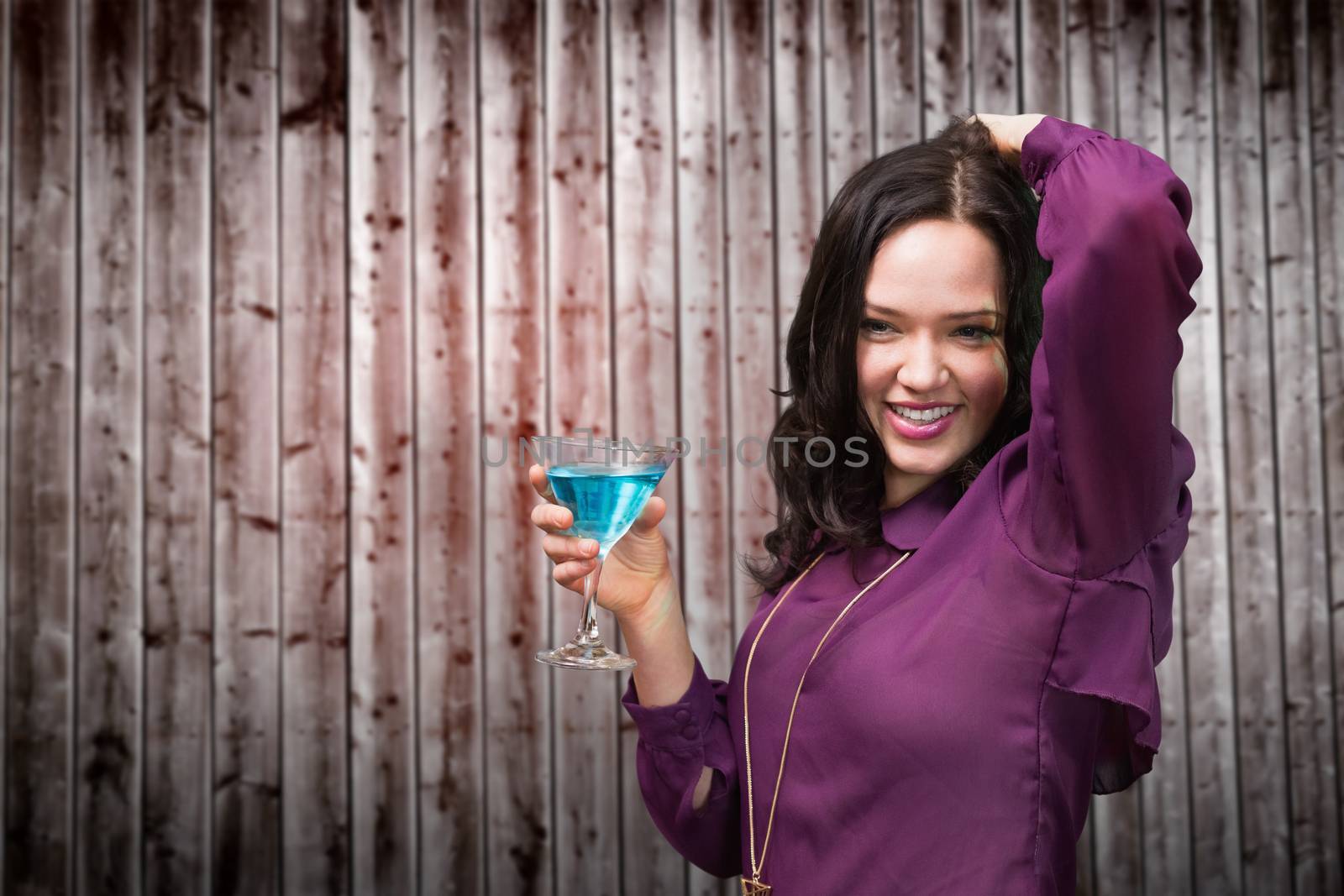 Brunette drinking cocktail against wooden planks