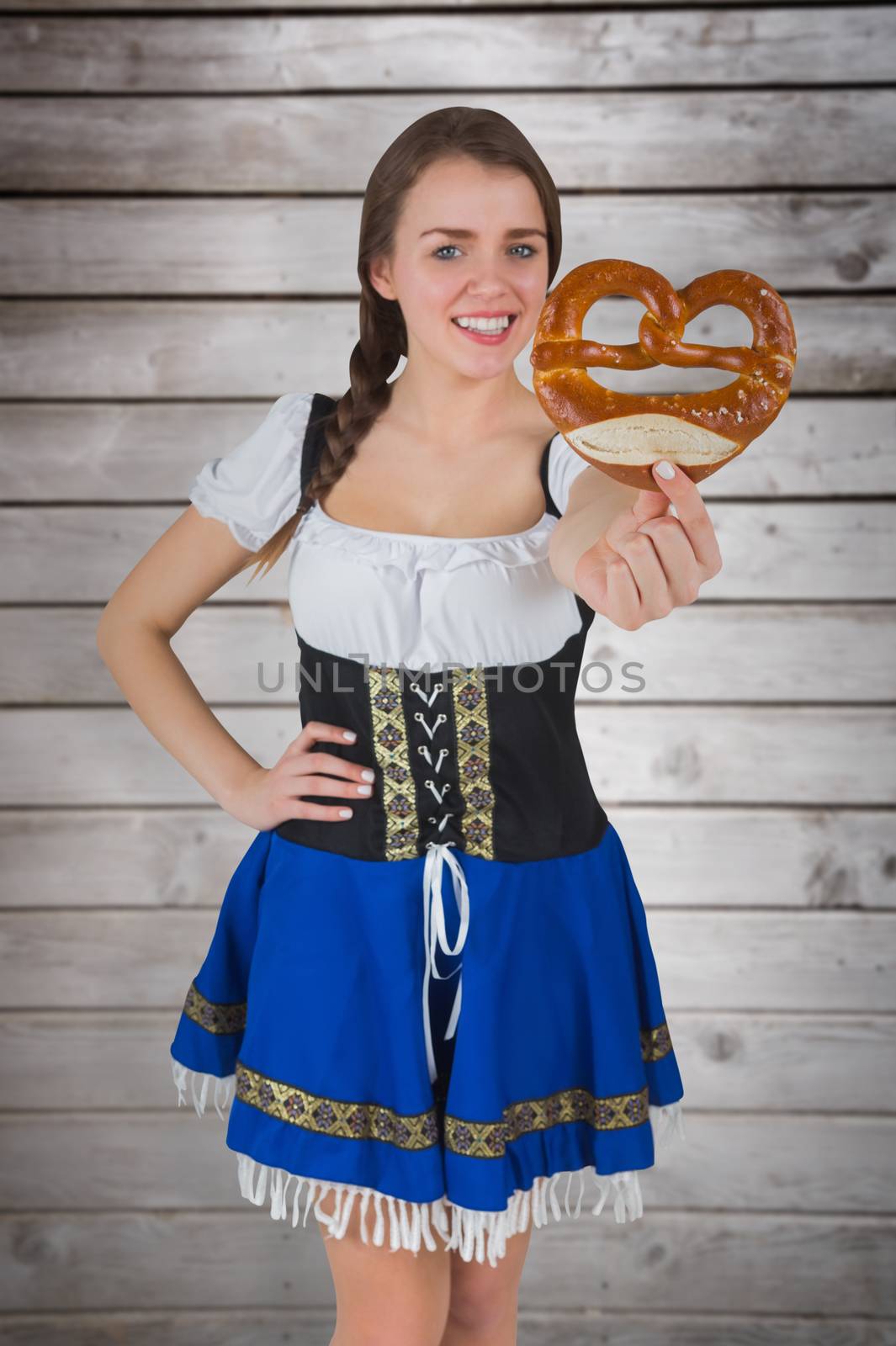 Pretty oktoberfest girl holding pretzel against wooden planks