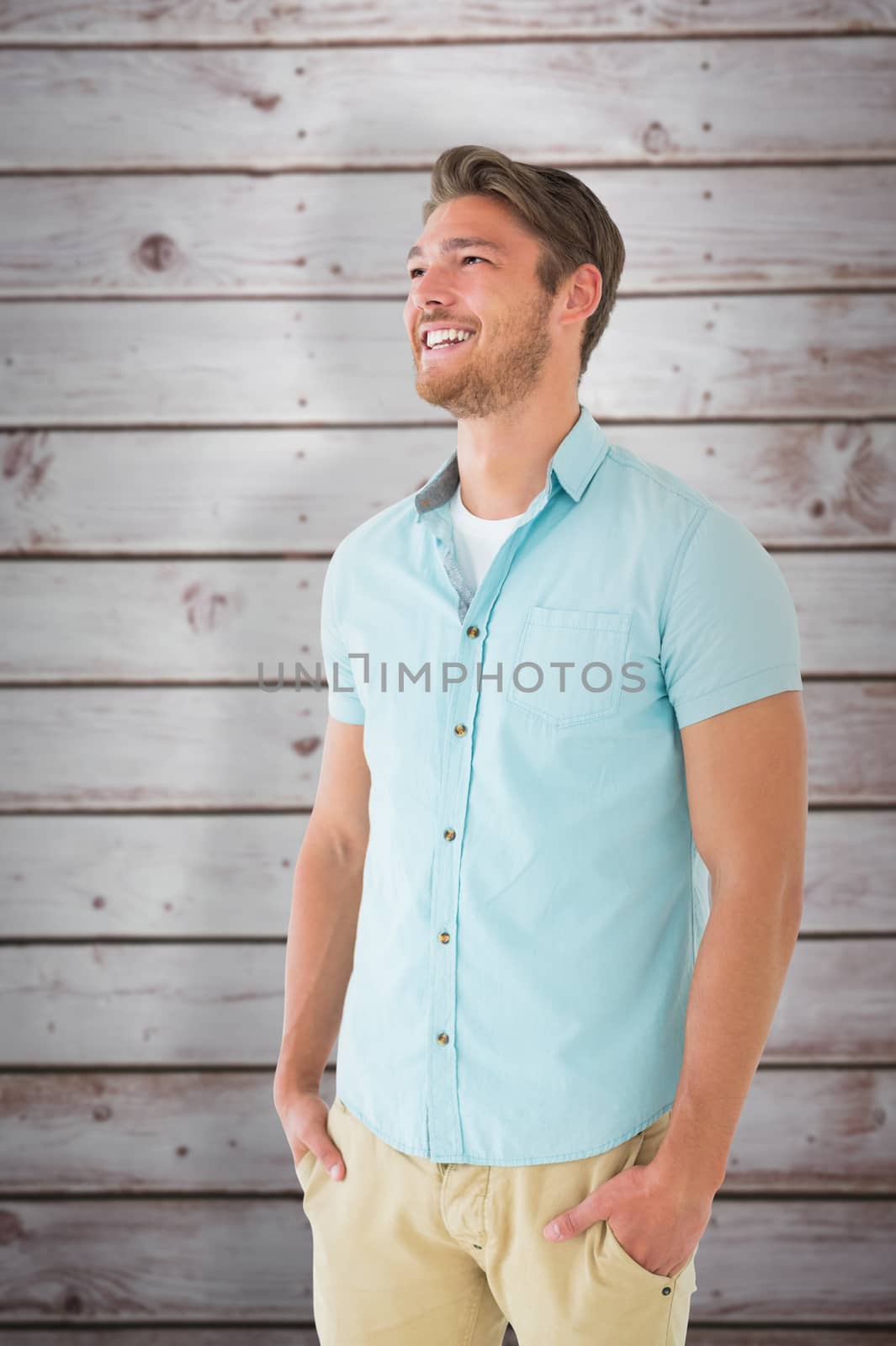 Handsome young man posing with hands in pockets against wooden planks