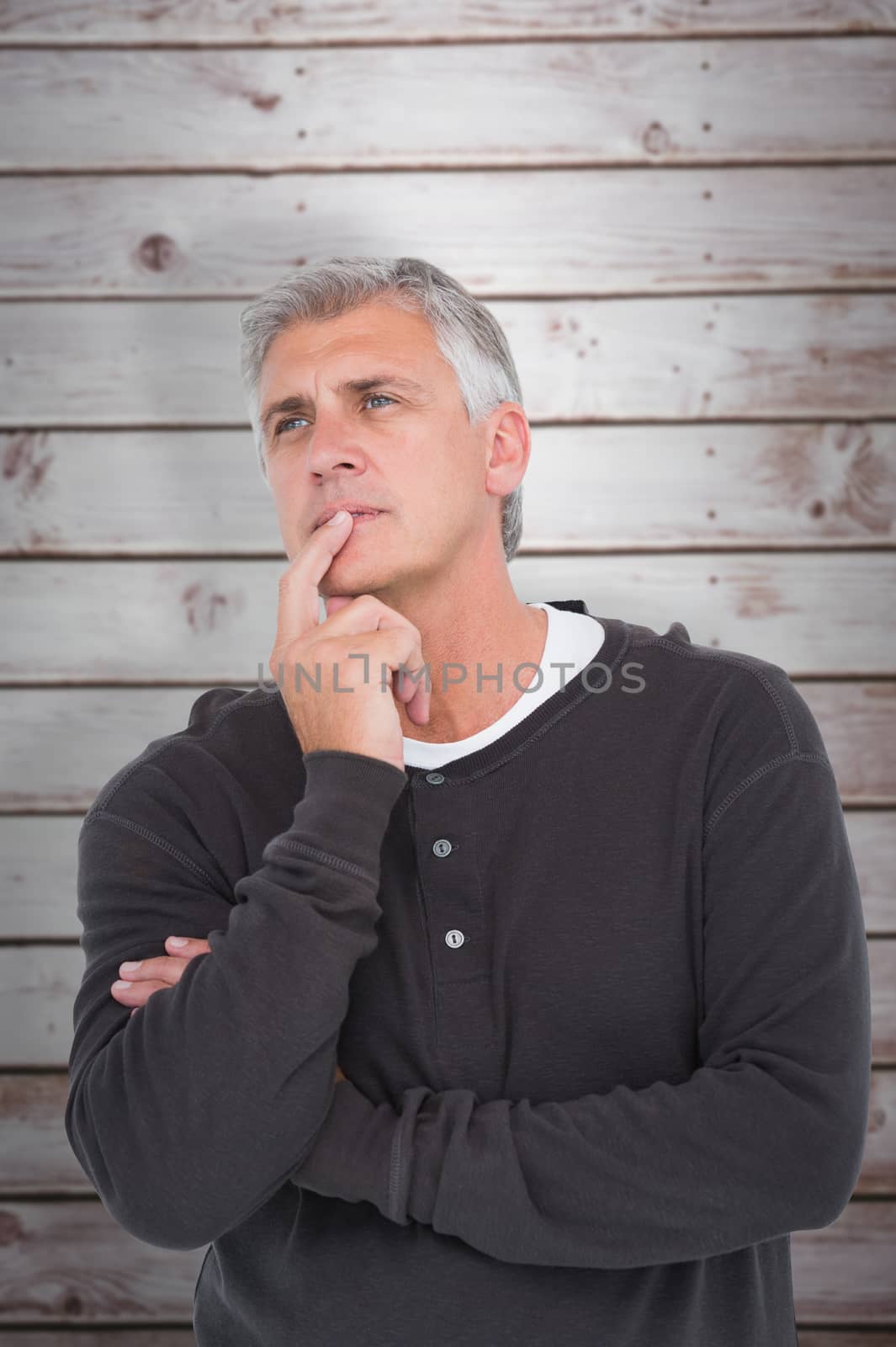 Casual man thinking with hand on chin against wooden planks